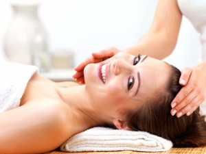 Portrait of a cheerful young female receiving facial massage